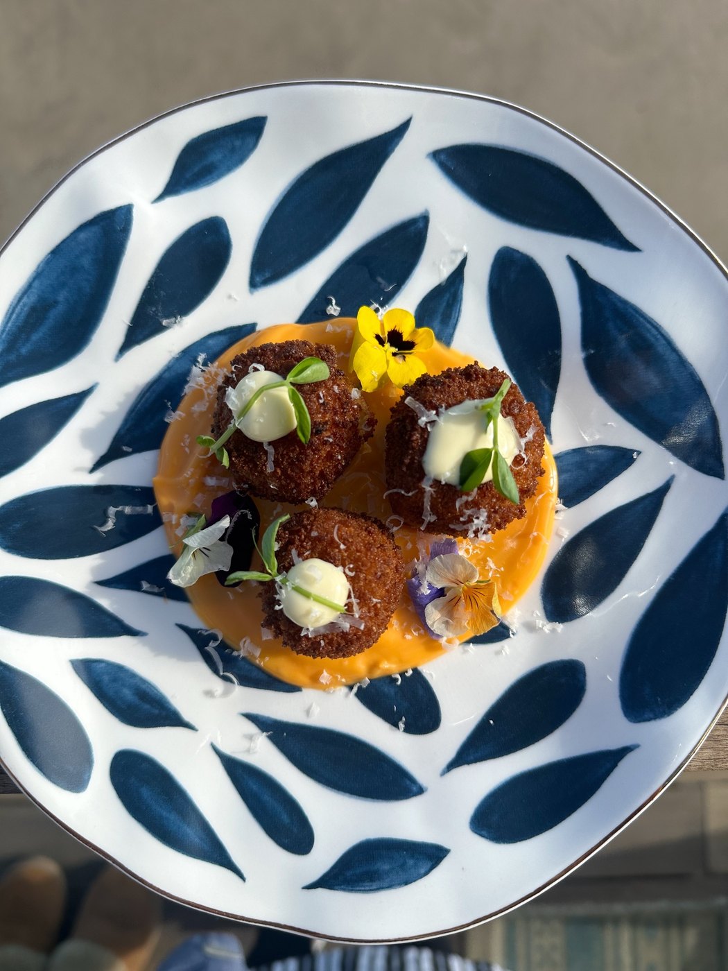 Crispy arancini on a saffron pool with edible flowers